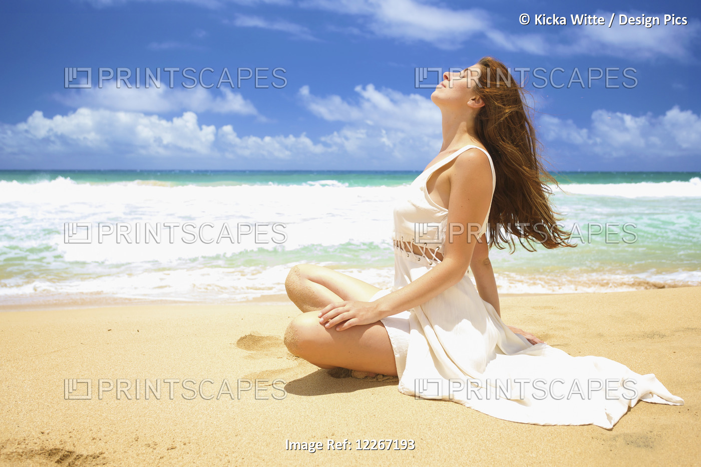 A Woman Sitting On The Sand At The Water's Edge Soaking Up The Sun; Kealia, ...