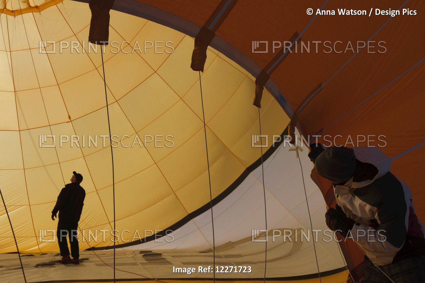 A Man Looks On As His Colleague Checks Ropes Inside A Hot Air Balloon As It ...