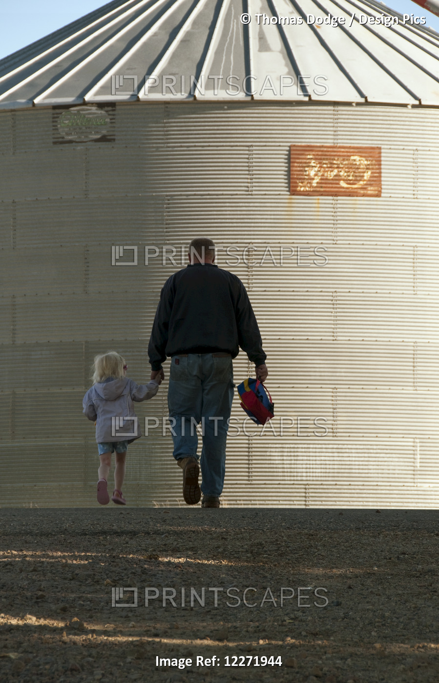 A Farmer And His Young Daughter Walk Hand-In-Hand Through His Farm Yard With A ...