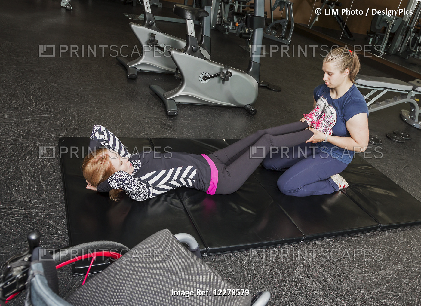 Physiotherapist Assisting Young Woman With Spinal Cord Injury In Performing ...