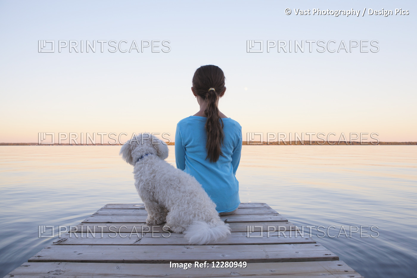 Girl Sitting With Her Dog At End Of Dock On Balsam Lake; Ontario, Canada