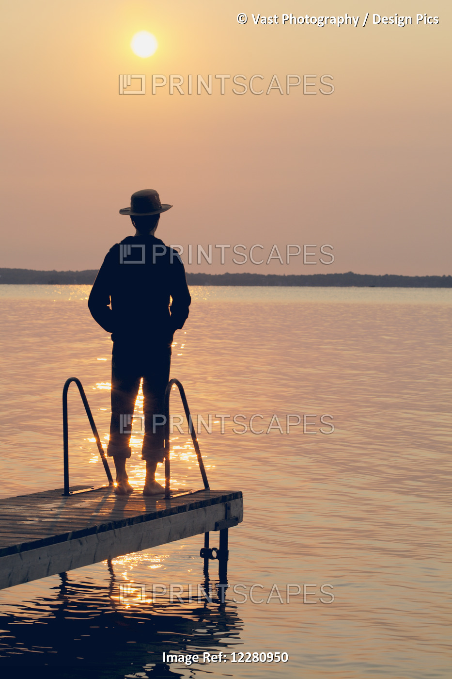 Man Standing At End Of Dock At Sunrise On Balsam Lake; Ontario, Canada