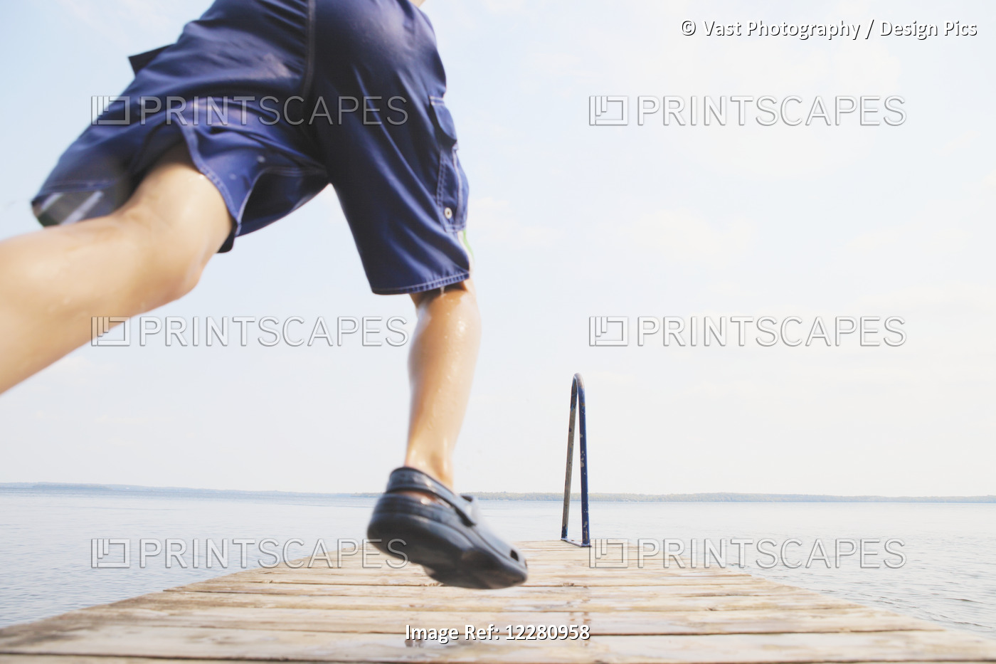 Boy Running To Jump Off End Of Dock On Balsam Lake; Ontario, Canada