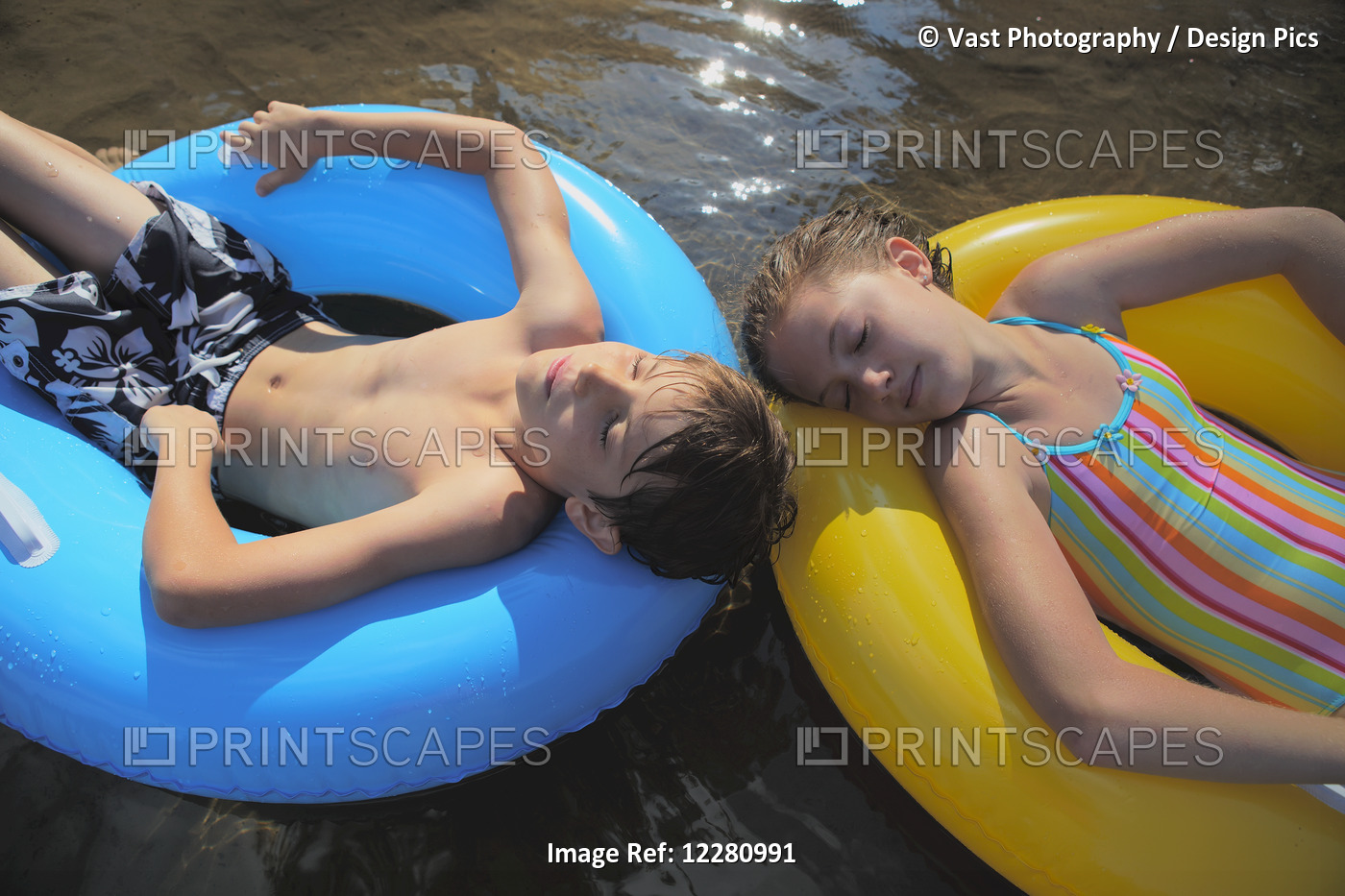Boy And Girl Floating With Inflatable Rings On Crystal Lake; Ontario, Canada