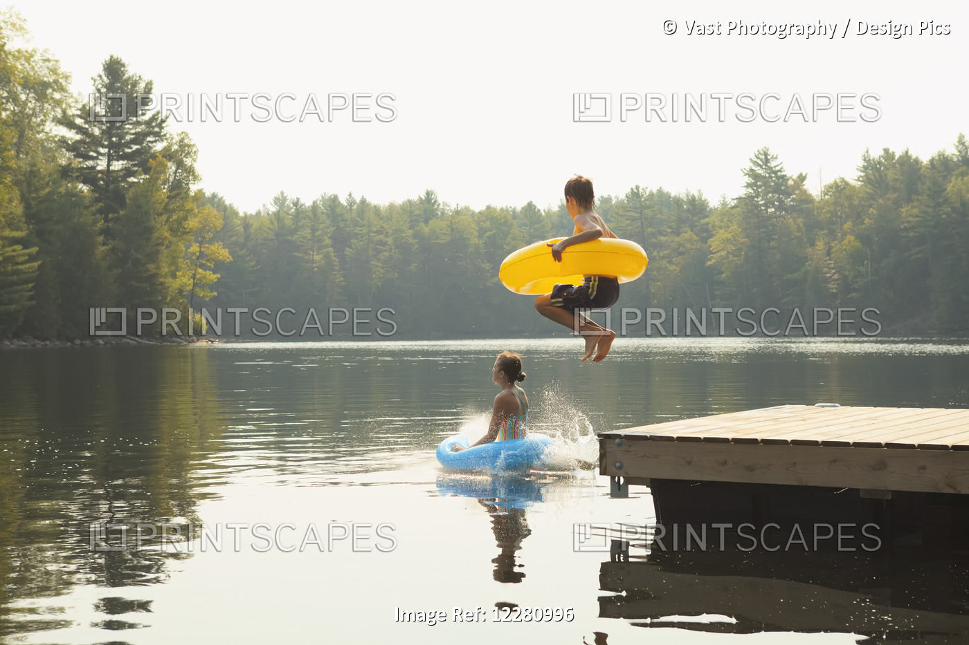 Kids Jumping Off End Of Dock Holding Inflatable Rings On Crystal Lake; Ontario, ...