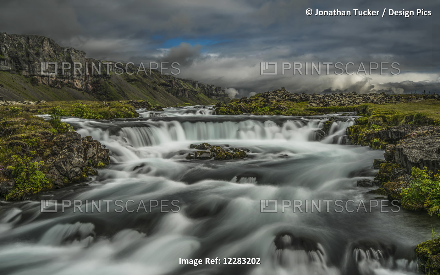 Water Flowing Over A Rugged Landscape Under A Cloudy Sky; Iceland