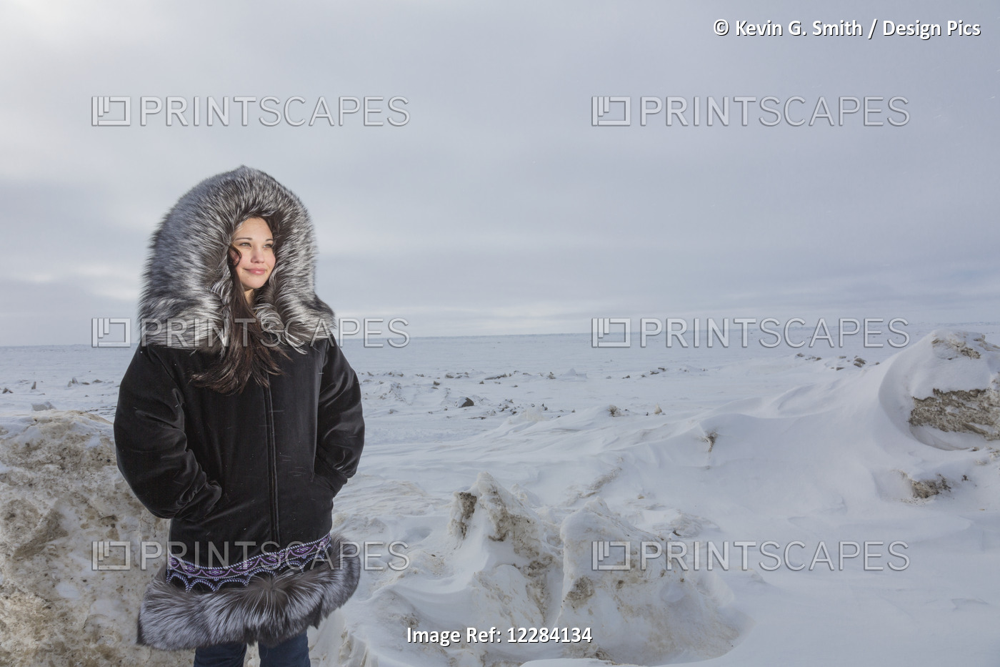Female Native Youth Wearing A Traditional Fur Parka While Standing On Ice Along ...