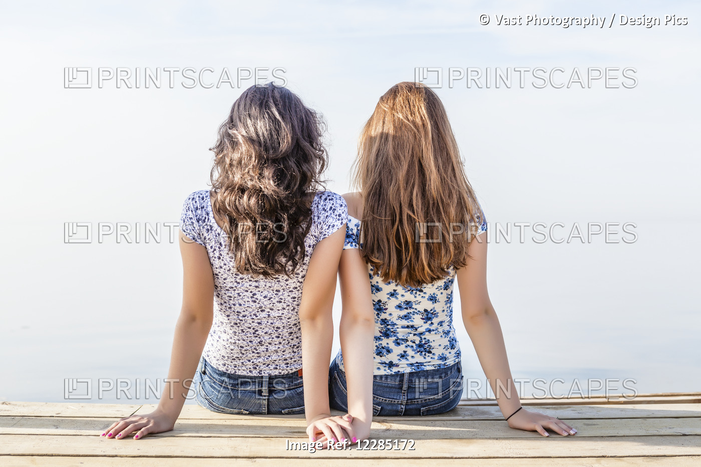 Two Girls Holding Hands Sitting Close Together At End Of A Dock; Toronto, ...