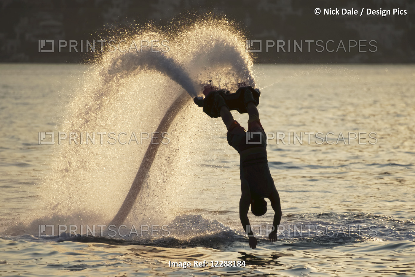 Silhouette Of Backlit Flyboarder Diving Vertically With Arms Stretched Out; ...