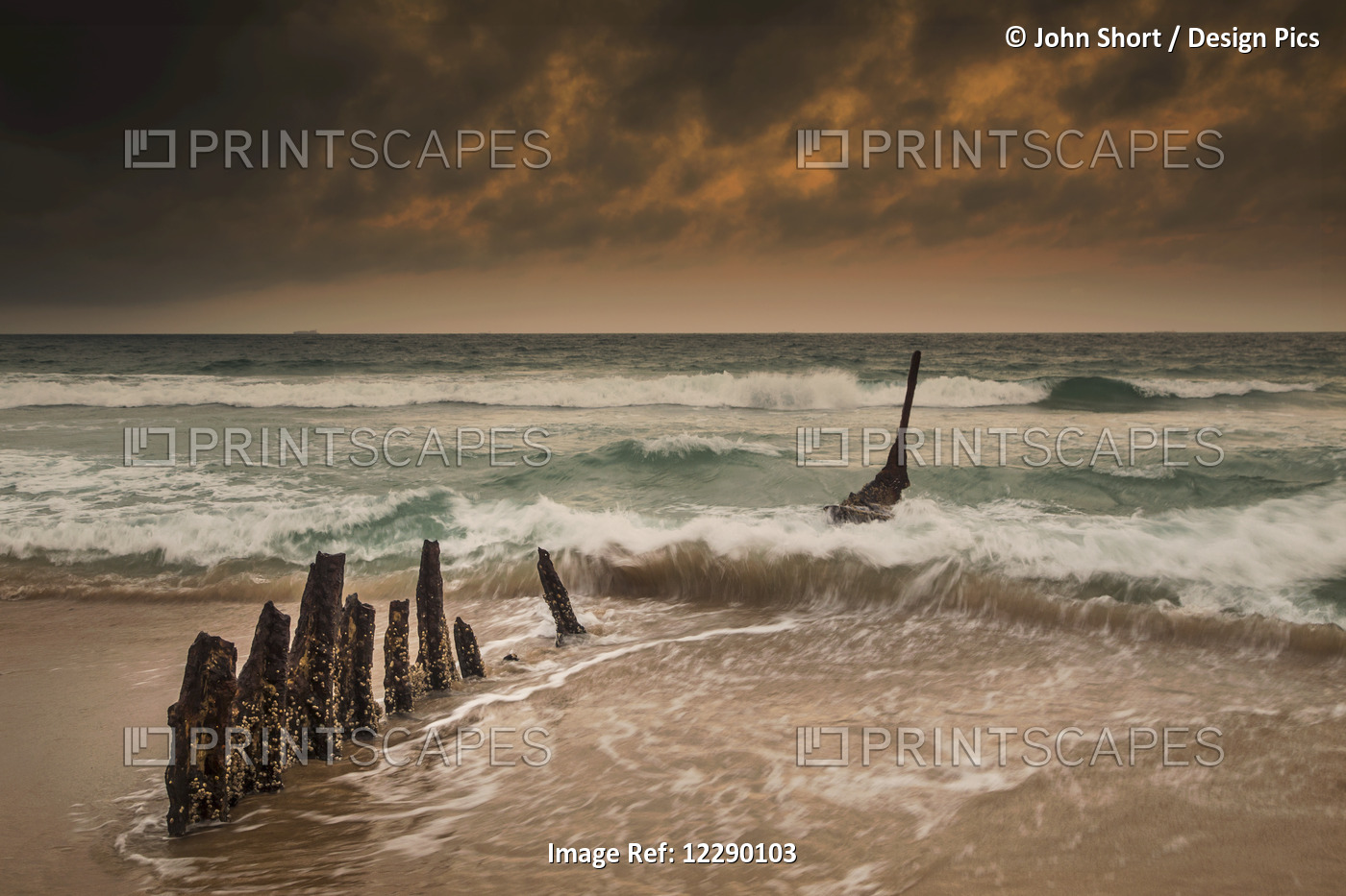 Wooden Posts On A Beach With A Boat Being Tossed In The Water And Waves ...