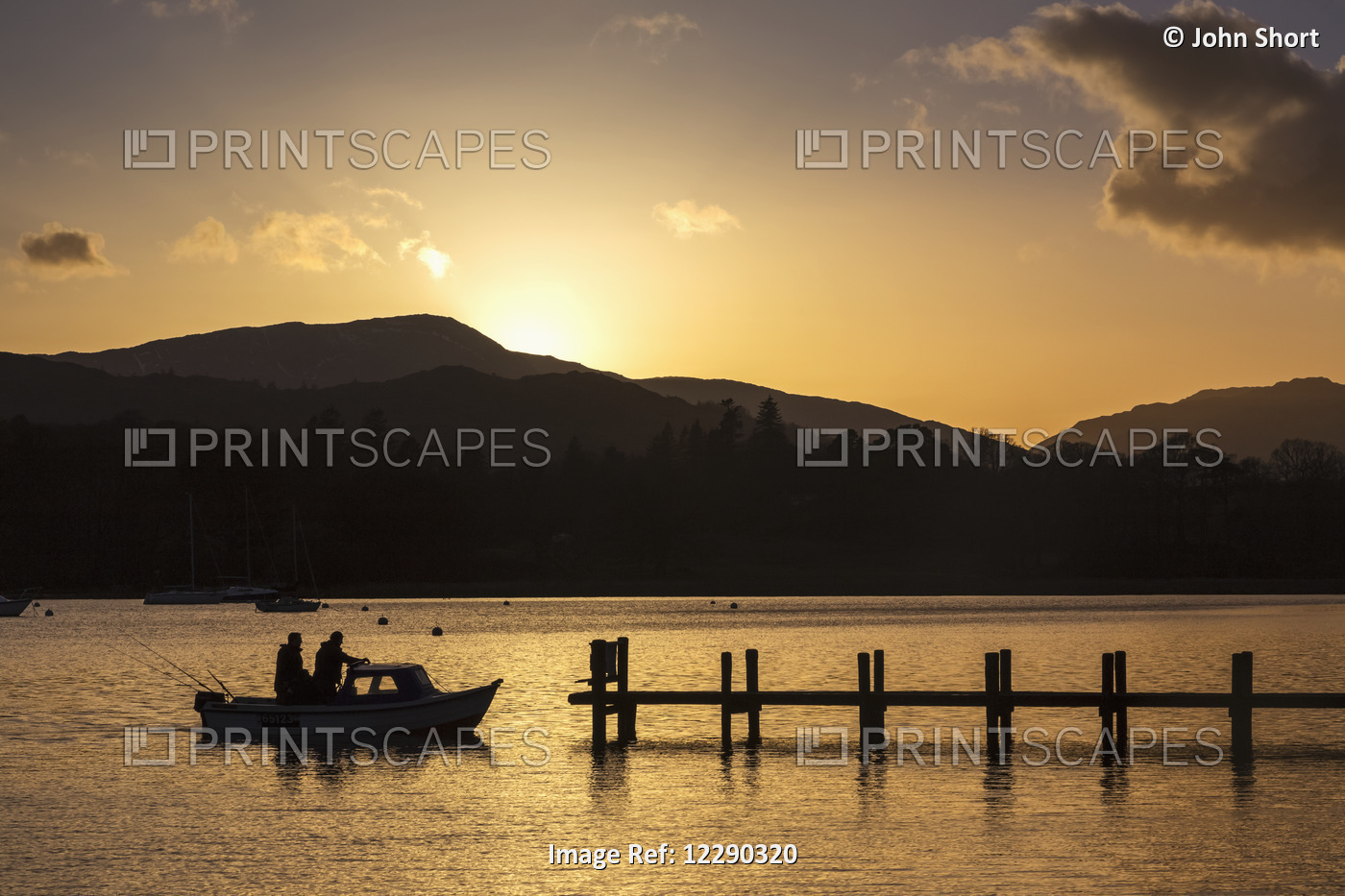 Silhouette Of Fishermen In A Boat Arriving At A Dock On A Lake At Sunset; ...