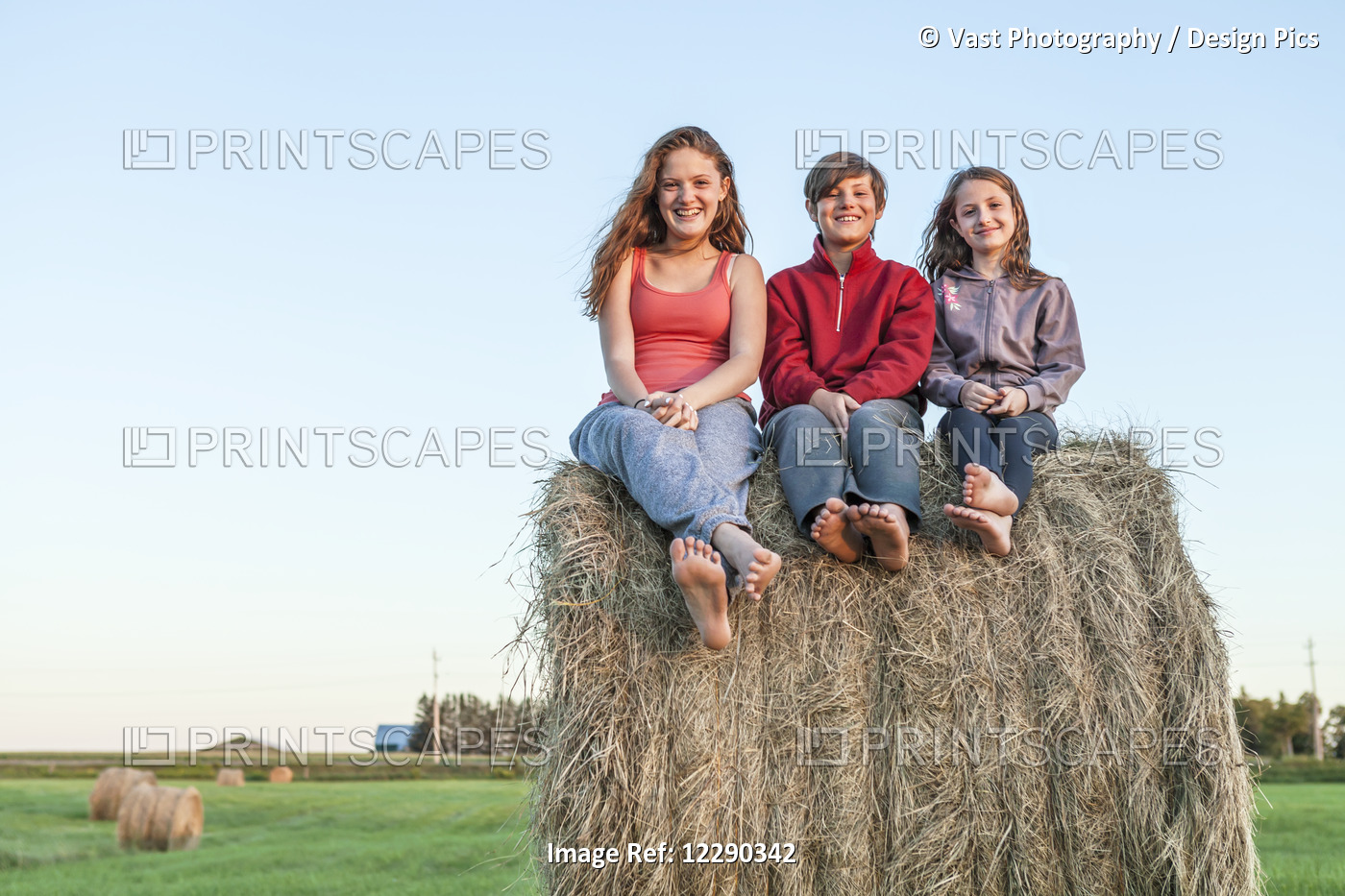 Three Kids Sitting On Hay Bale; Ontario, Canada