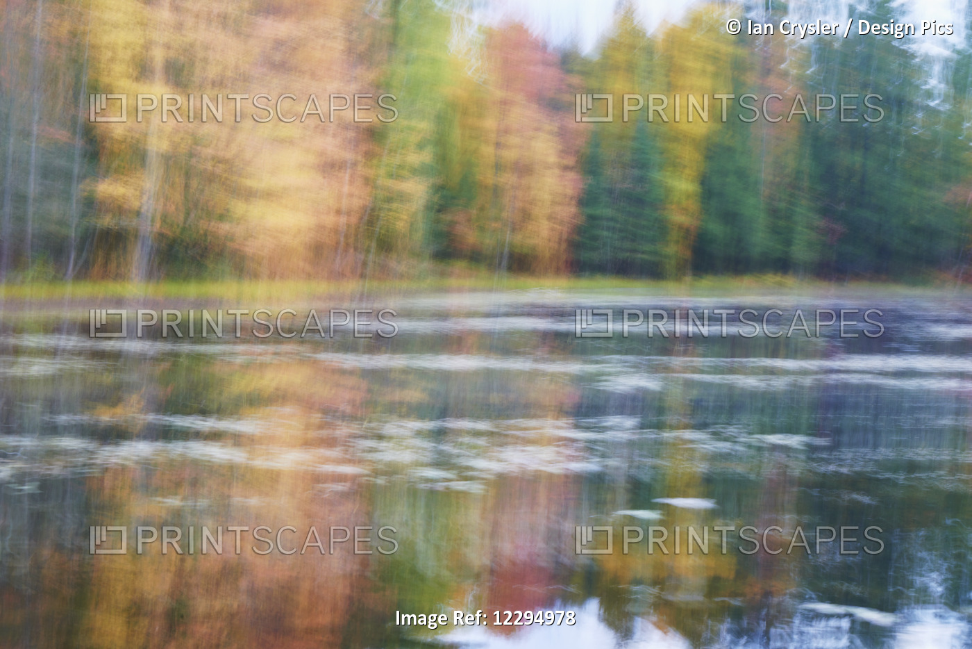 Blurred Autumn Coloured Trees Along The Shoreline Reflected In A Tranquil ...