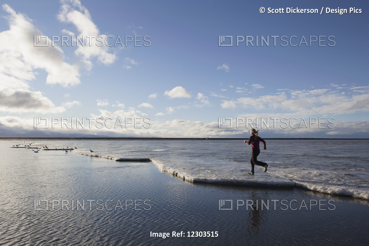 Woman Running On The Ice Covered Beach In Homer, Kenai Peninsula, Southcentral ...