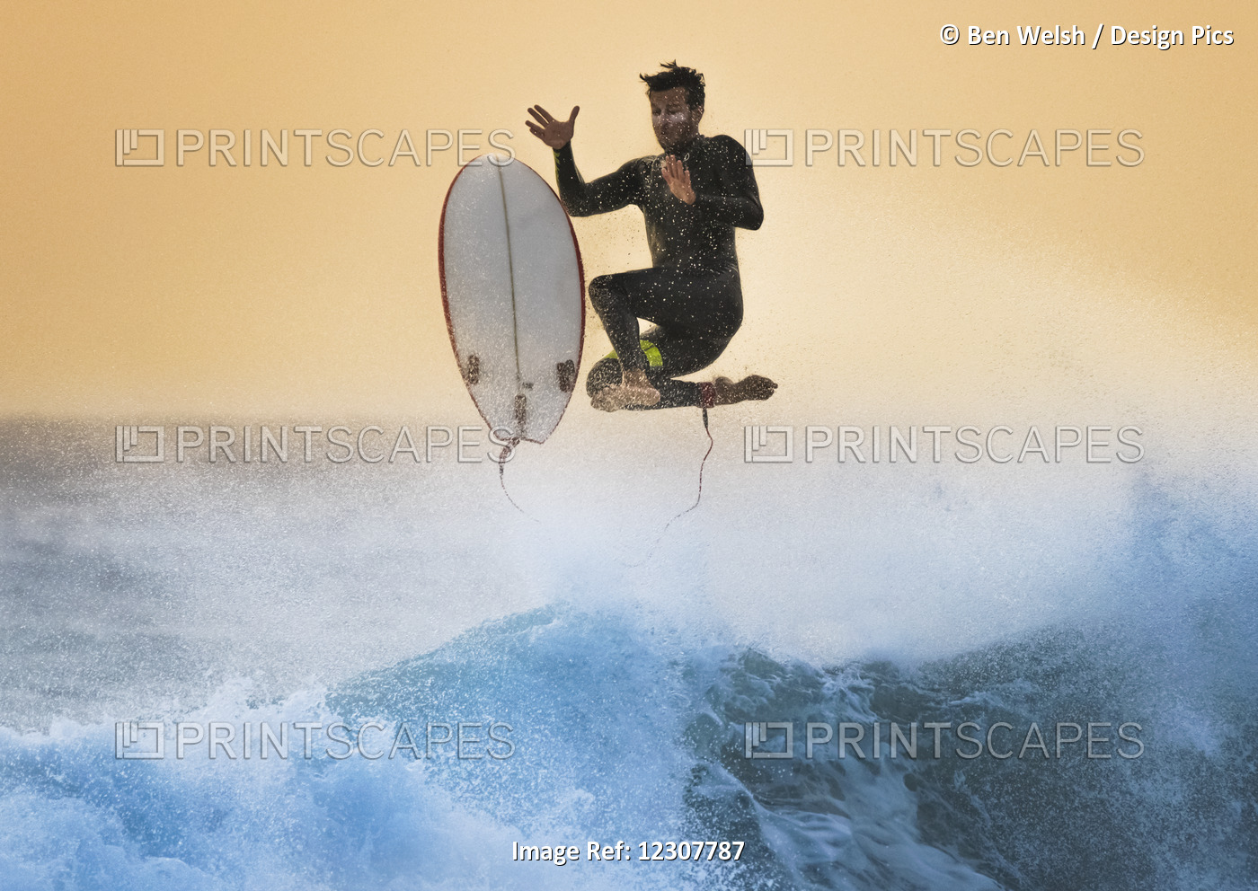 A Man Leaps In The Air Off His Surfboard Over A Wave And Splashing Water With A ...