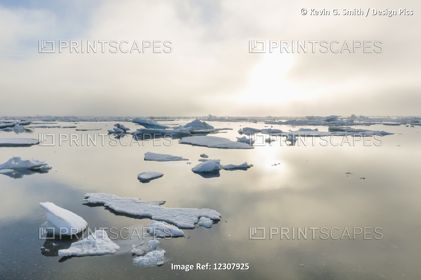 A Foggy Sunset Over The Arctic Ocean Illuminates Icebergs On A Partly Clear And ...