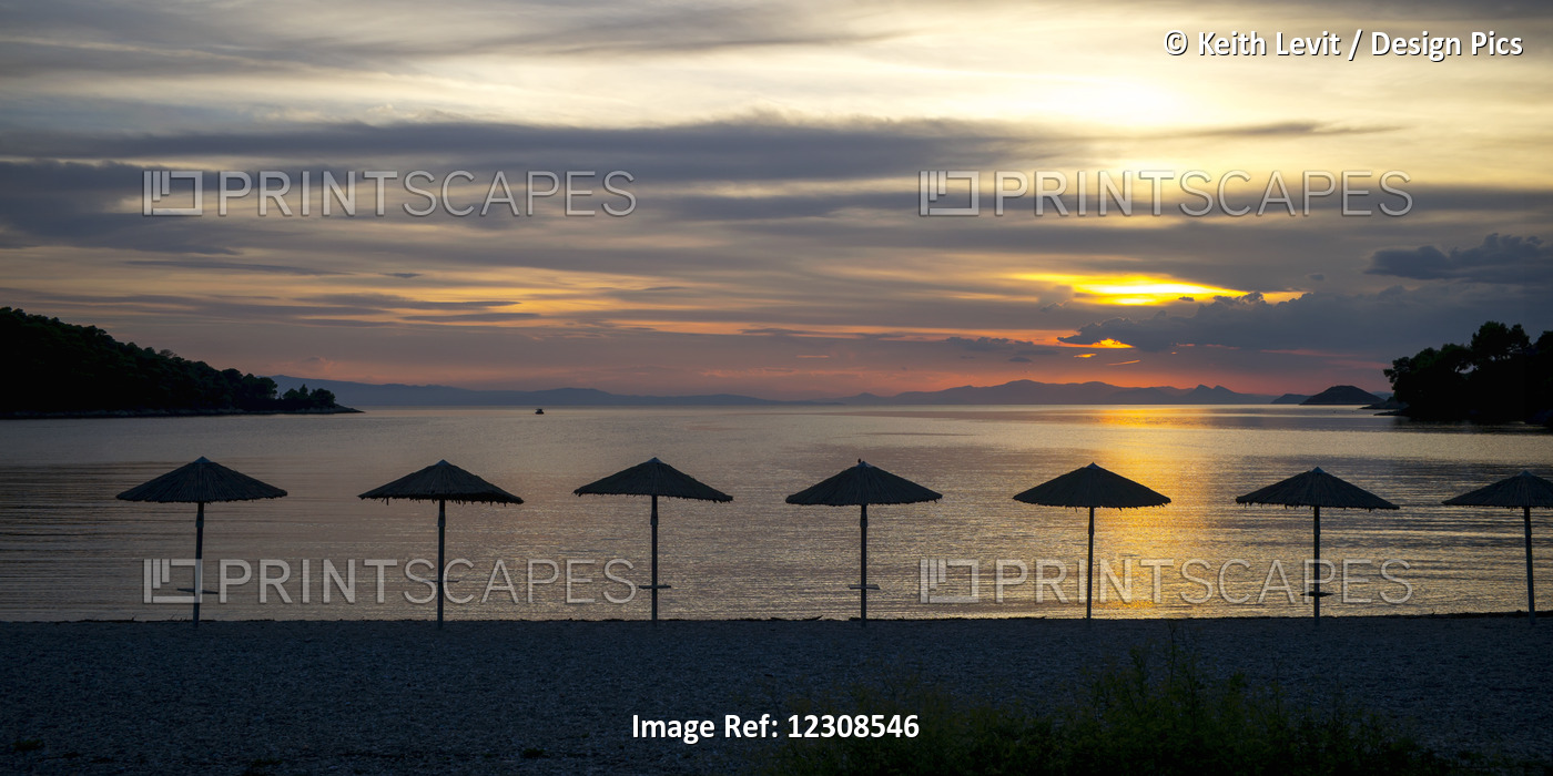 Silhouette Of Umbrellas On The Beach At Sunset On A Greek Island Along The ...