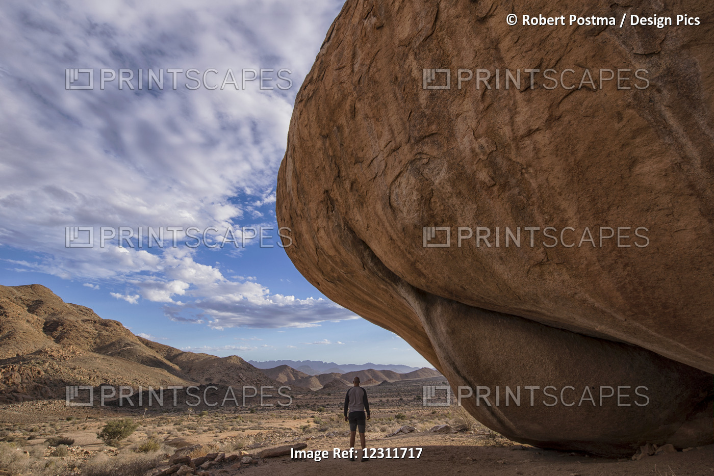 Man Standing Under A Huge Boulder In Richtersveld National Park; South Africa