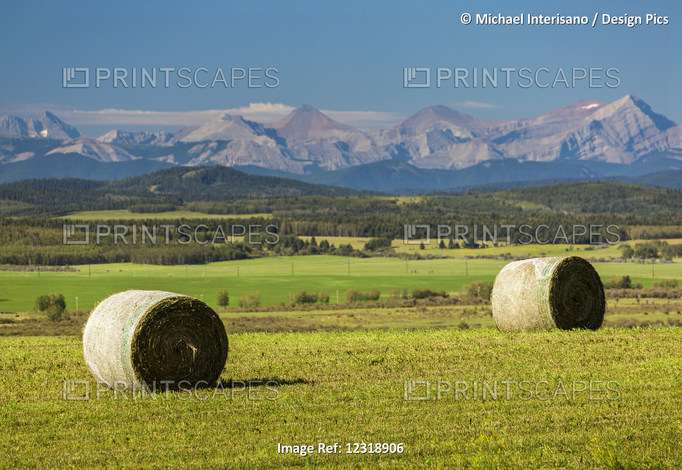 Two Large Round Hay Bales In A Cut Field With Rolling Foothills, Mountain Range ...