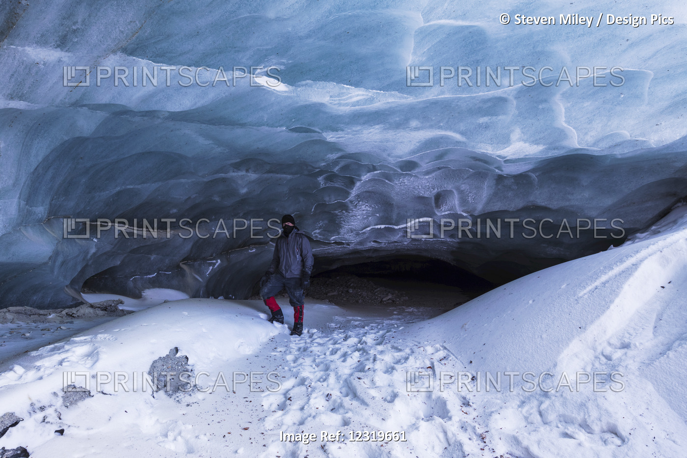 A Man Poses In Front Of A Cave At The Terminus Of Fels Glacier (Commonly ...