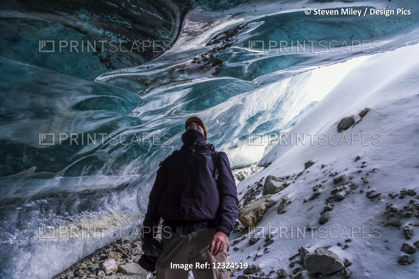 A Man Looks Up At The Ice Of Canwell Glacier While Standing In The Entrance To ...