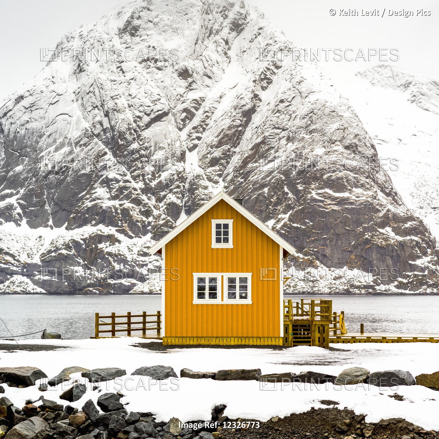 A Bright Yellow Building On The Water's Edge With A Snow Covered Mountain In ...