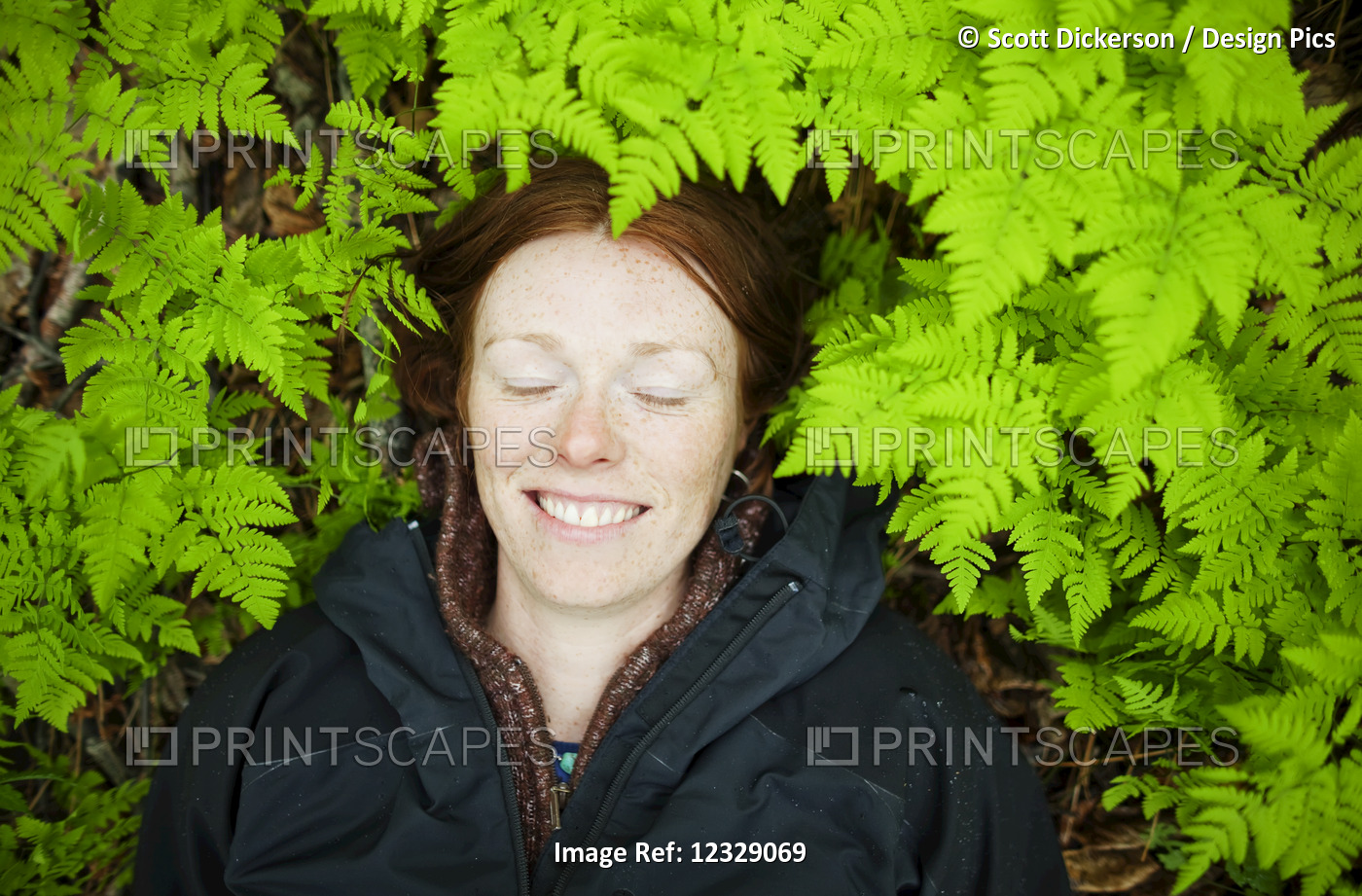 A Woman Lays Her Head On The Forest Floor Among The Bright Green, Lush Ferns; ...