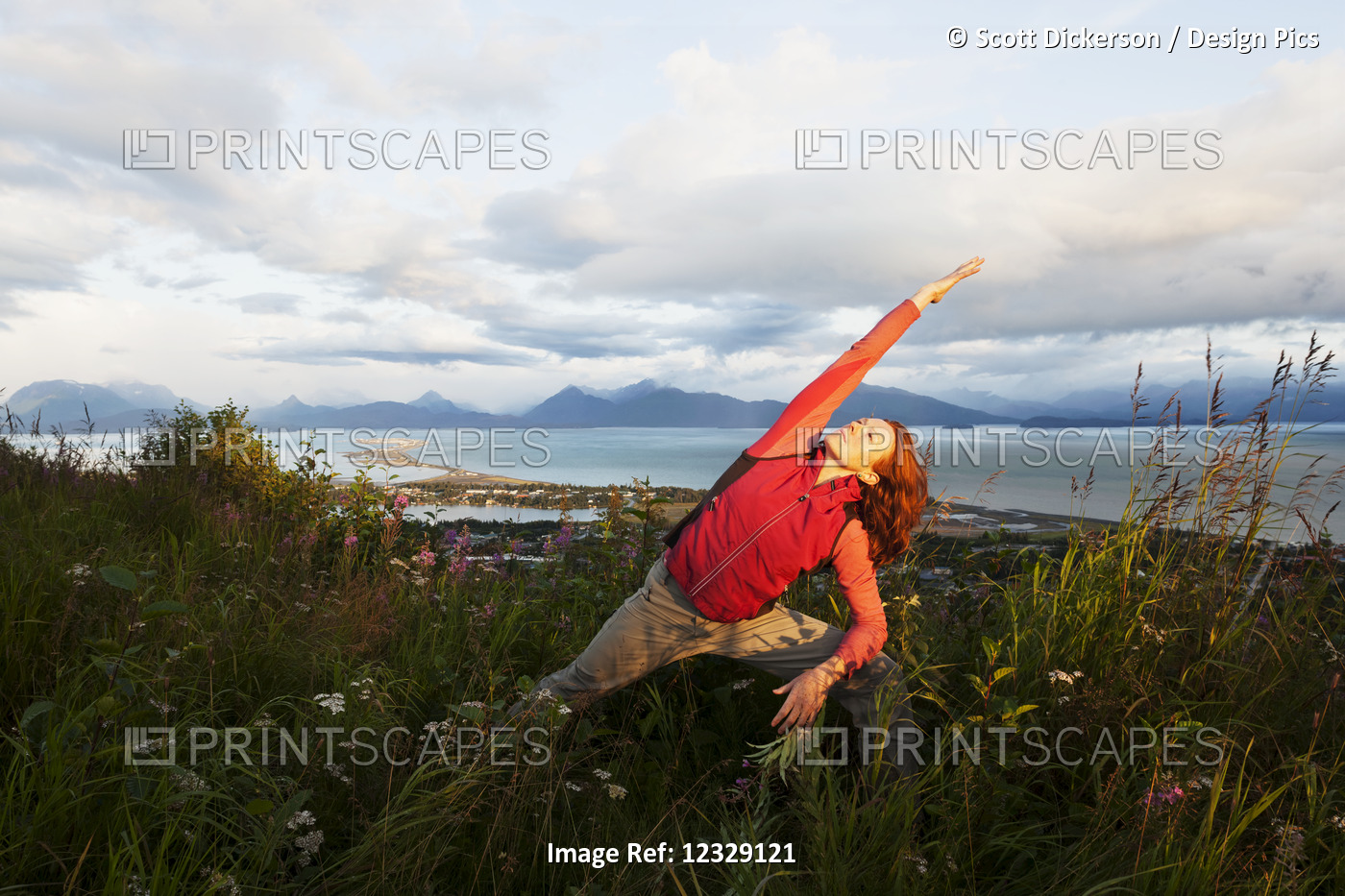 A Woman Doing Yoga In A Meadow With A View Of Homer Spit, Kachemak Bay And The ...