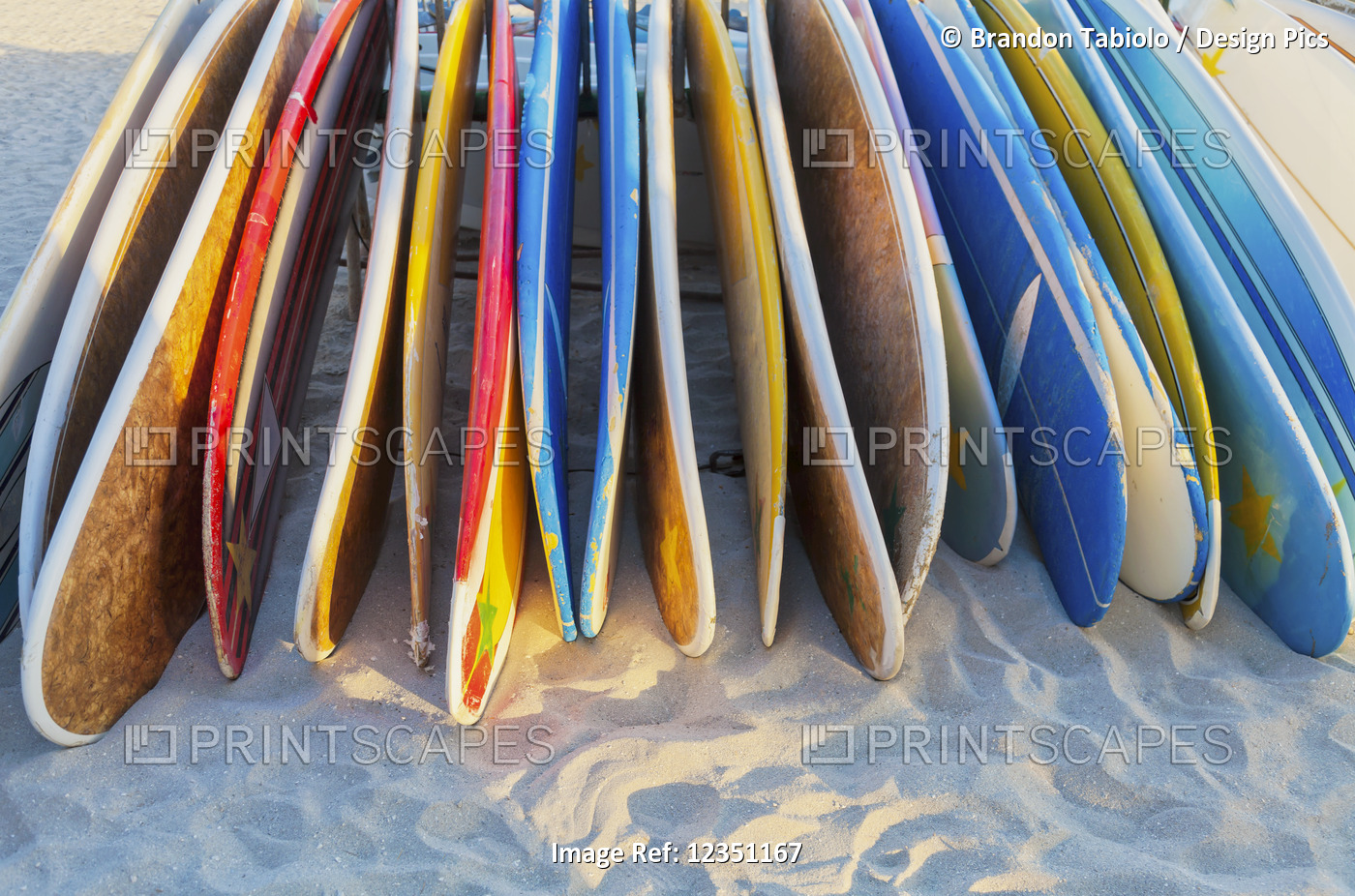 A stack of colourful longboard surfboards placed on the beach,; Waikiki, Oahu, ...