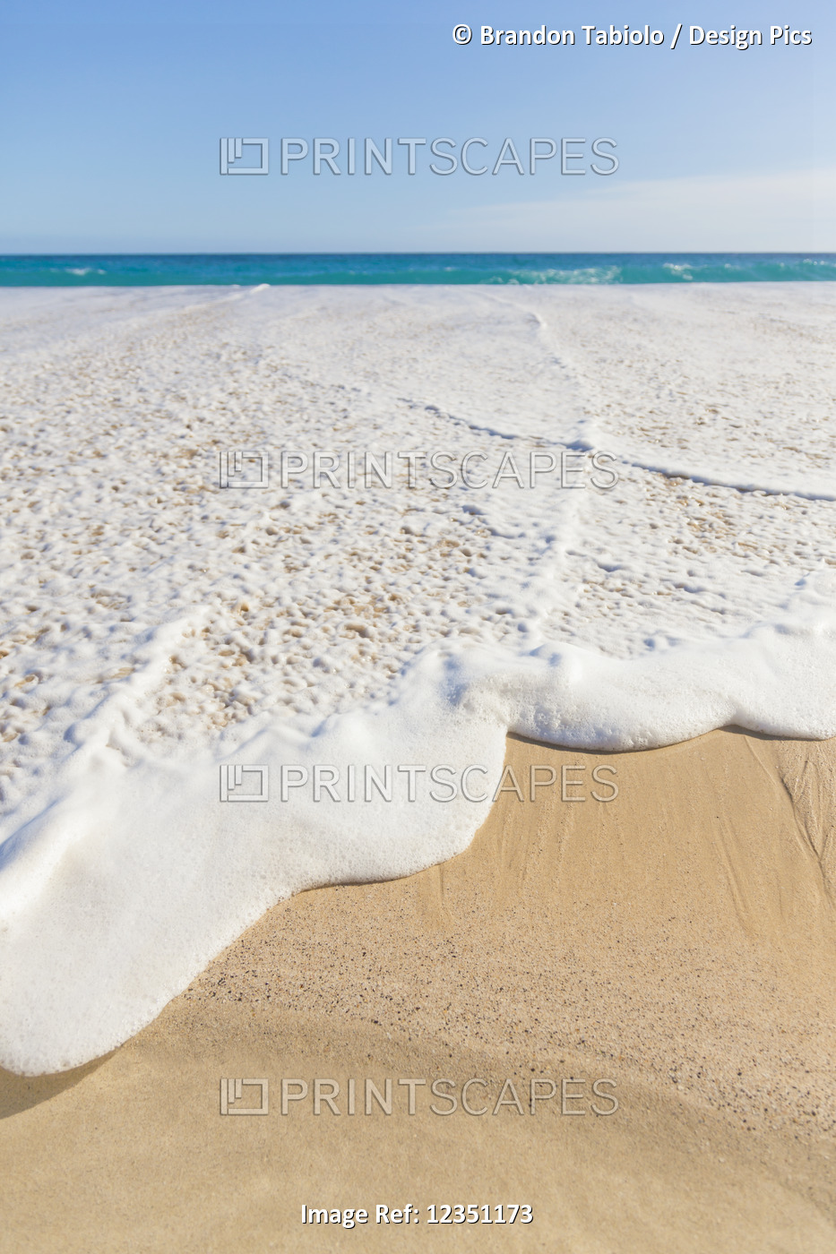 The ocean whitewash sea foam rising high onto the sand at the beach on the ...