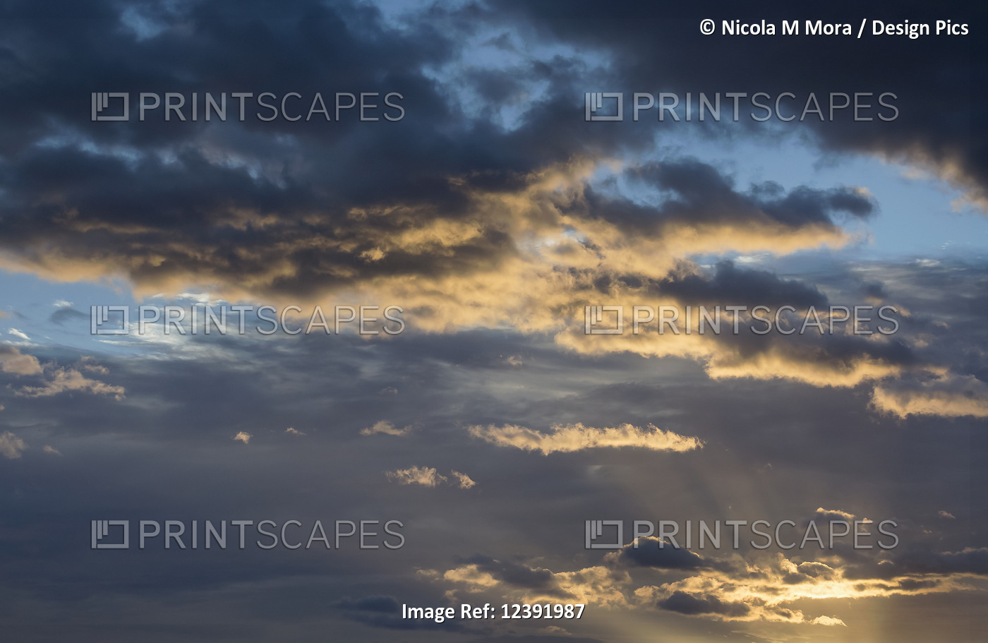Sun rays shining through storm clouds at sunset; Greymouth, New Zealand
