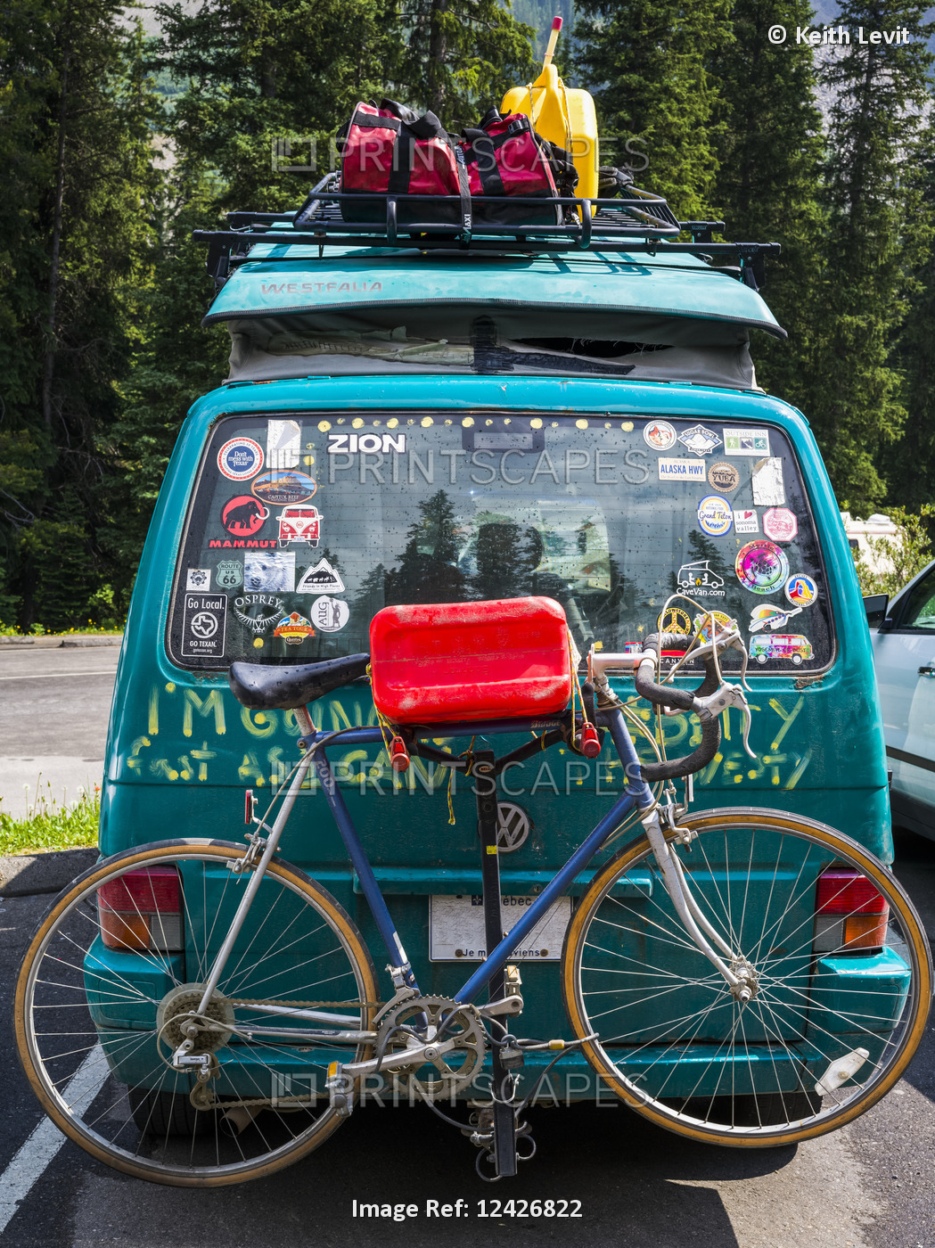 A camper van in a parking lot covered with bumper stickers and graffiti, and ...