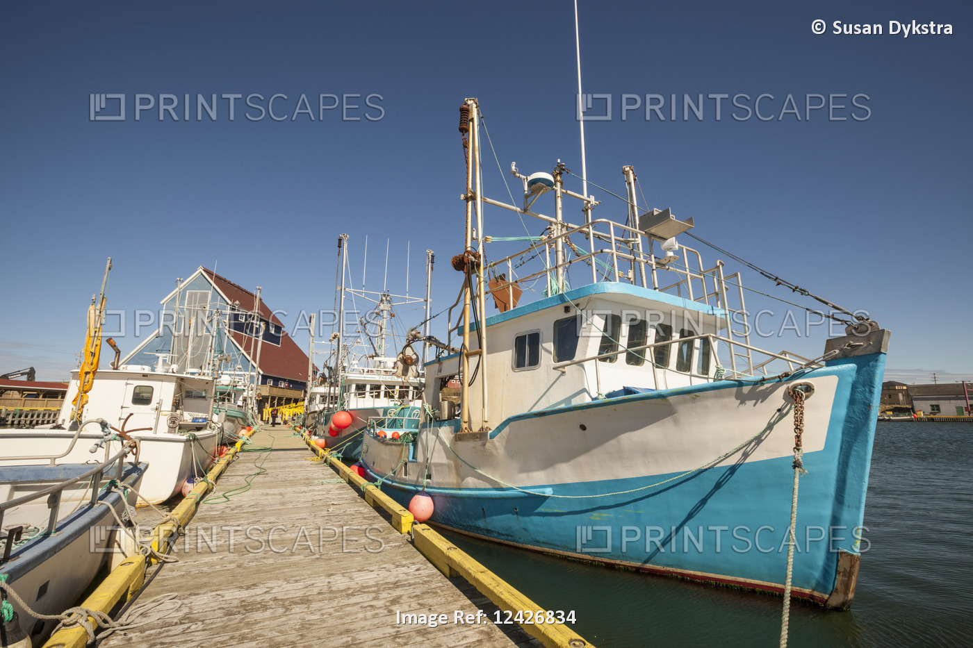 Fishing boats docked in a harbour along a wooden dock on the Atlantic coast; ...