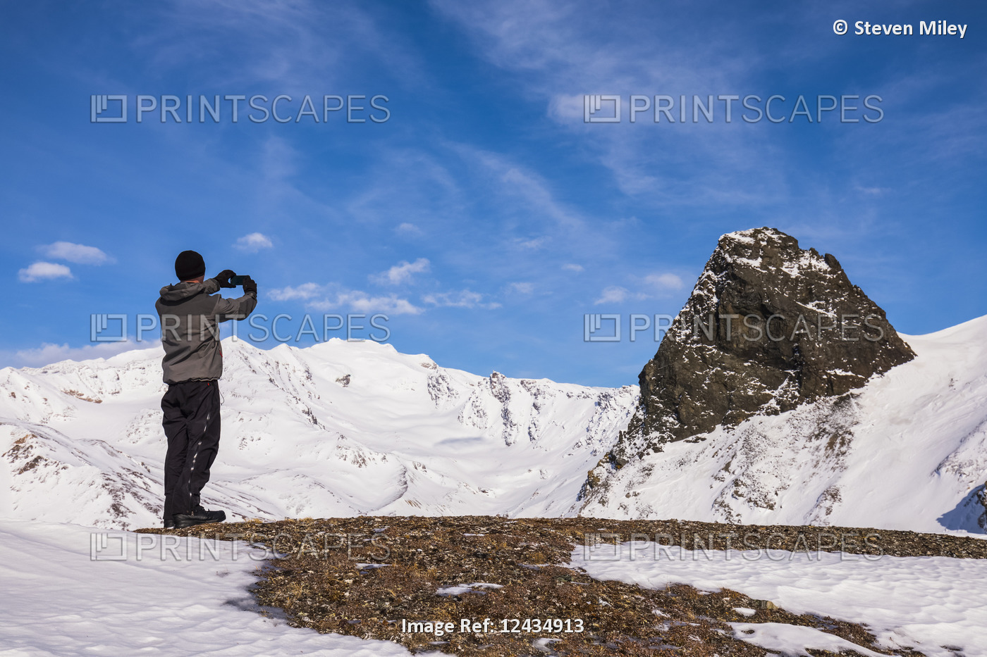 A man on a ridge in the eastern Alaska Range takes a picture of a large rock ...