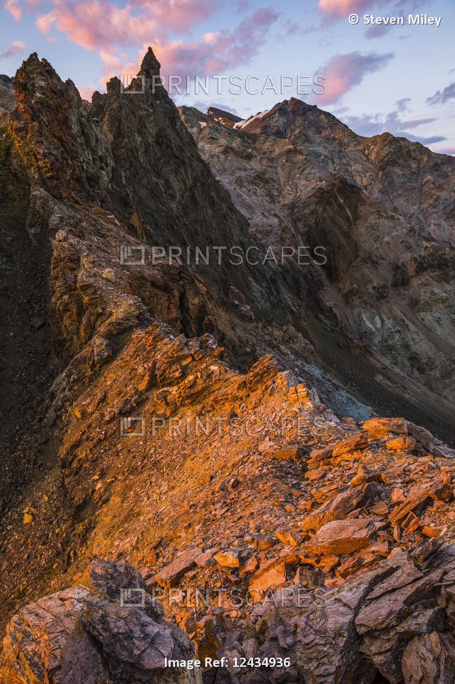 A craggy rock spire rises into the sky at sunset in the eastern Alaska Range; ...