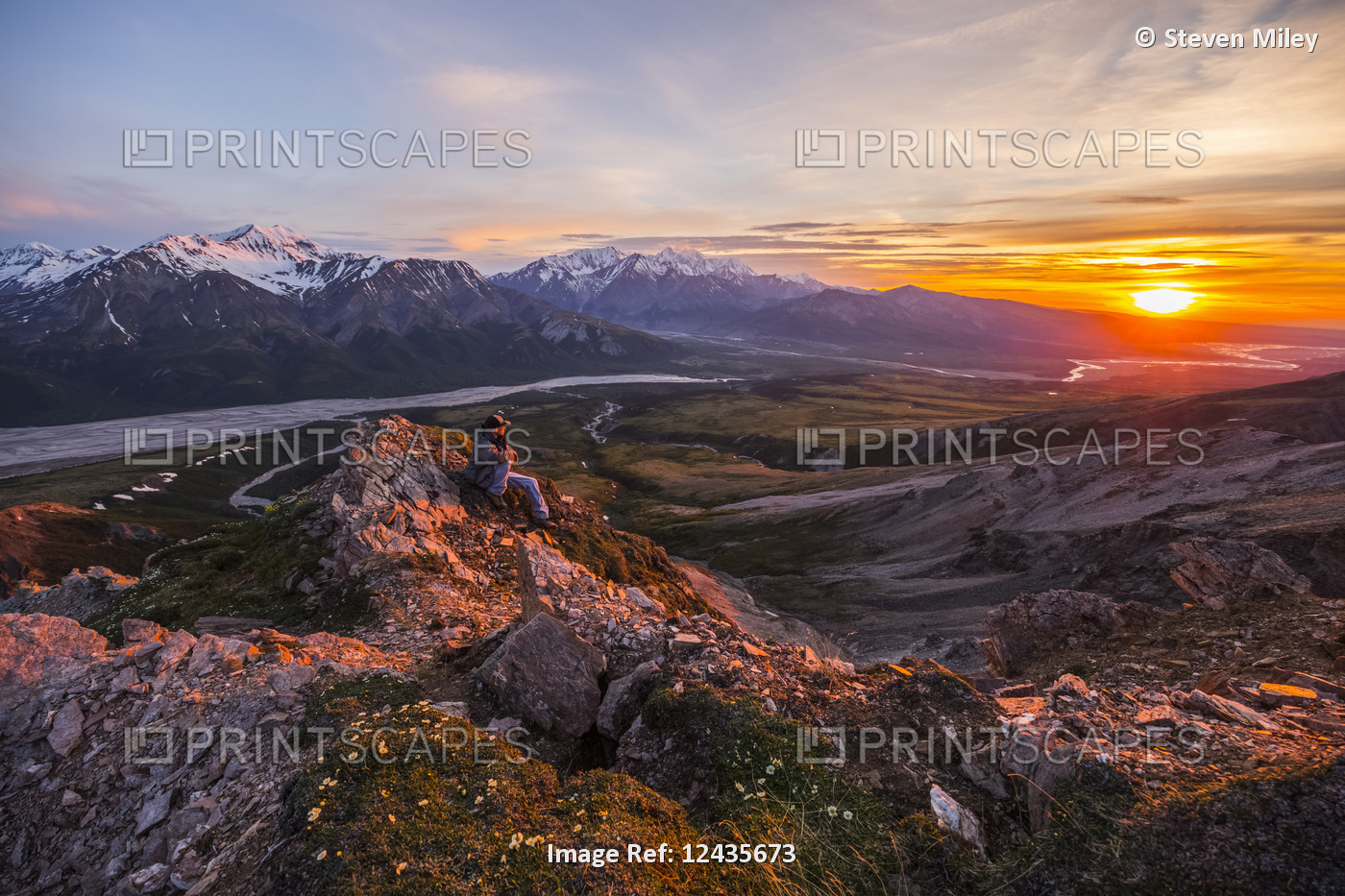 A man observes a tranquil sunset from an alpine perch high above the Delta ...