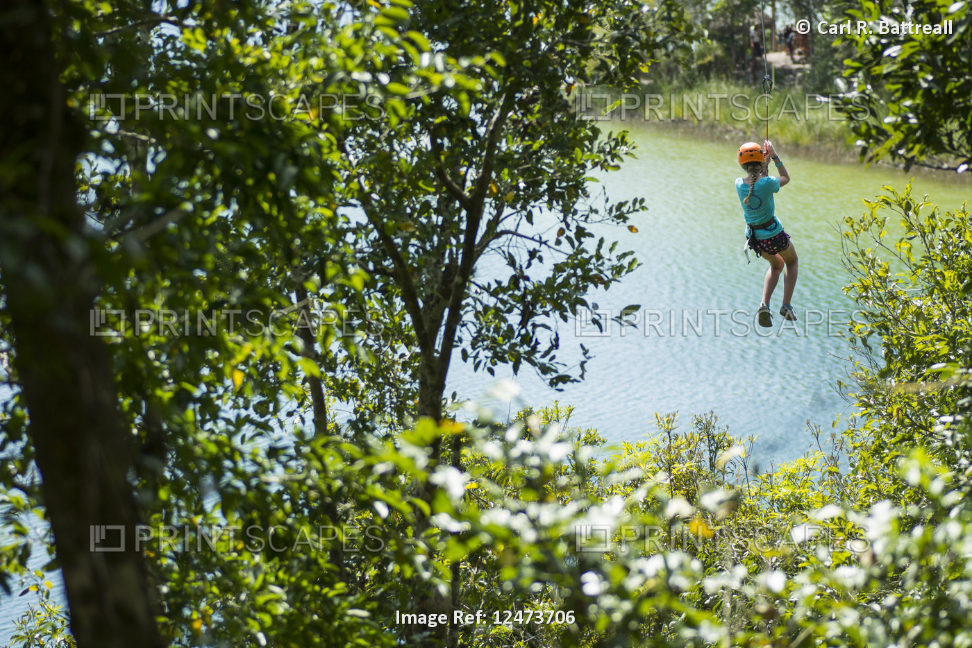 Teenage girl zip-lining over a lake; Yucatan, Mexico