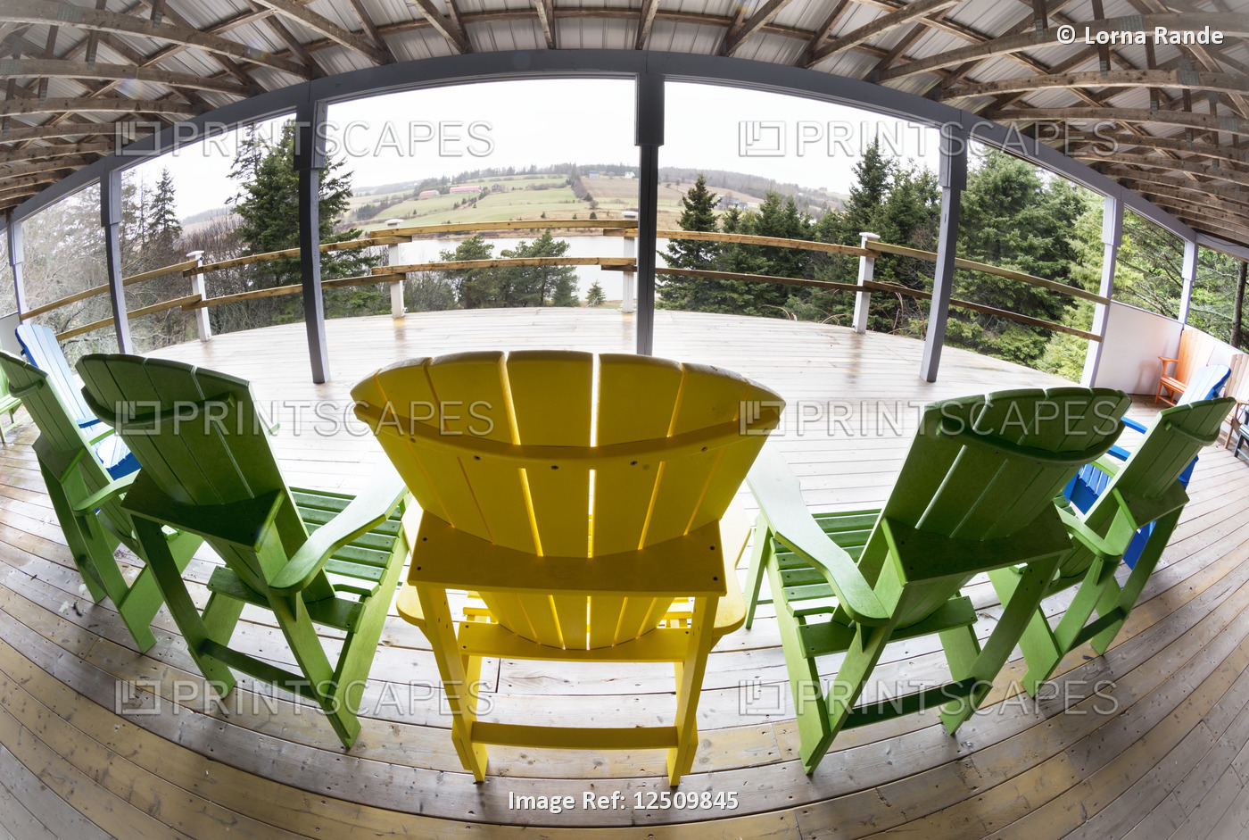 Yellow and green adirondack chairs on a wooden covered deck with a view, ...
