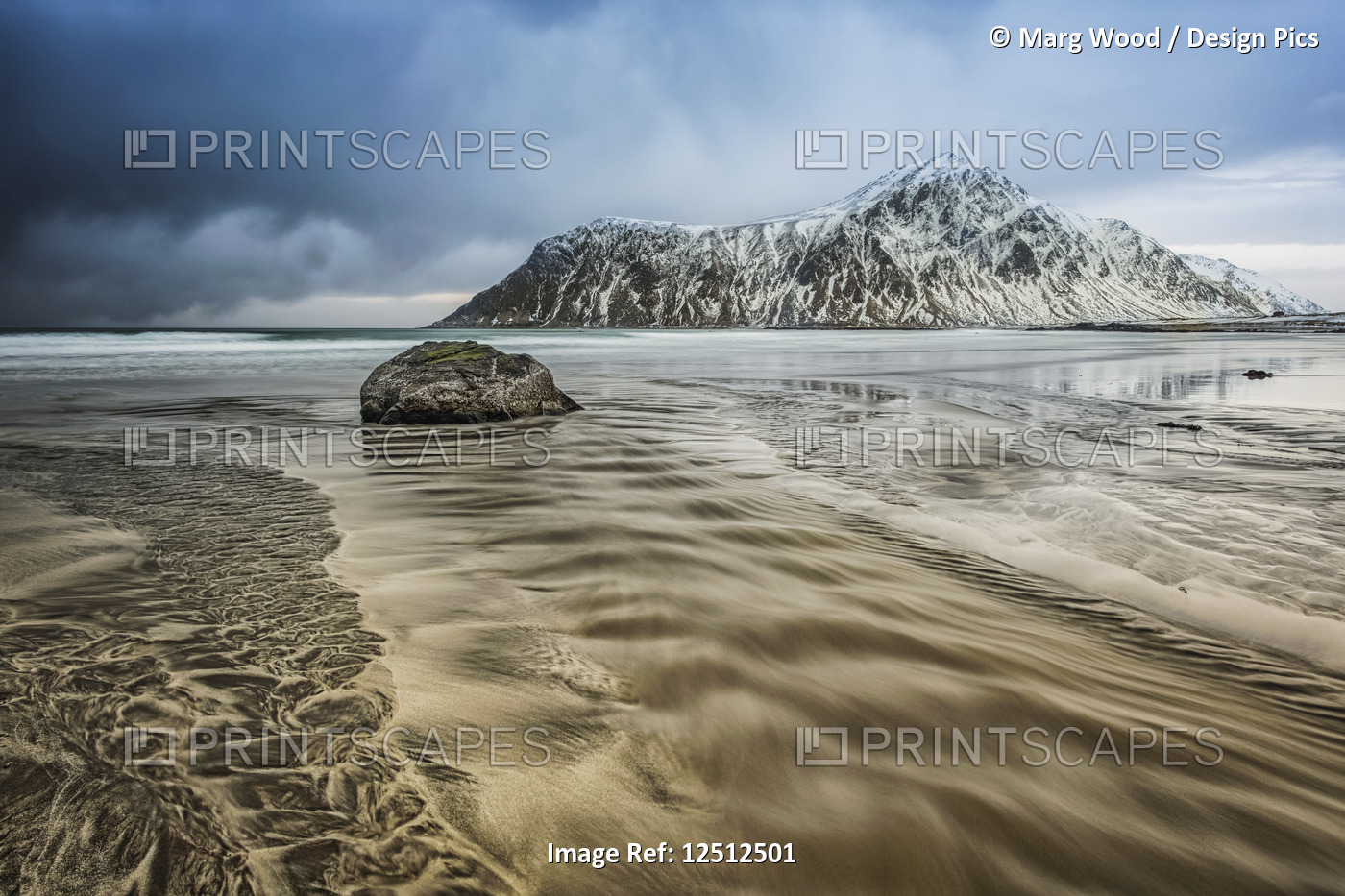 A landscape with rugged mountains and sand along the coastline under a cloudy ...
