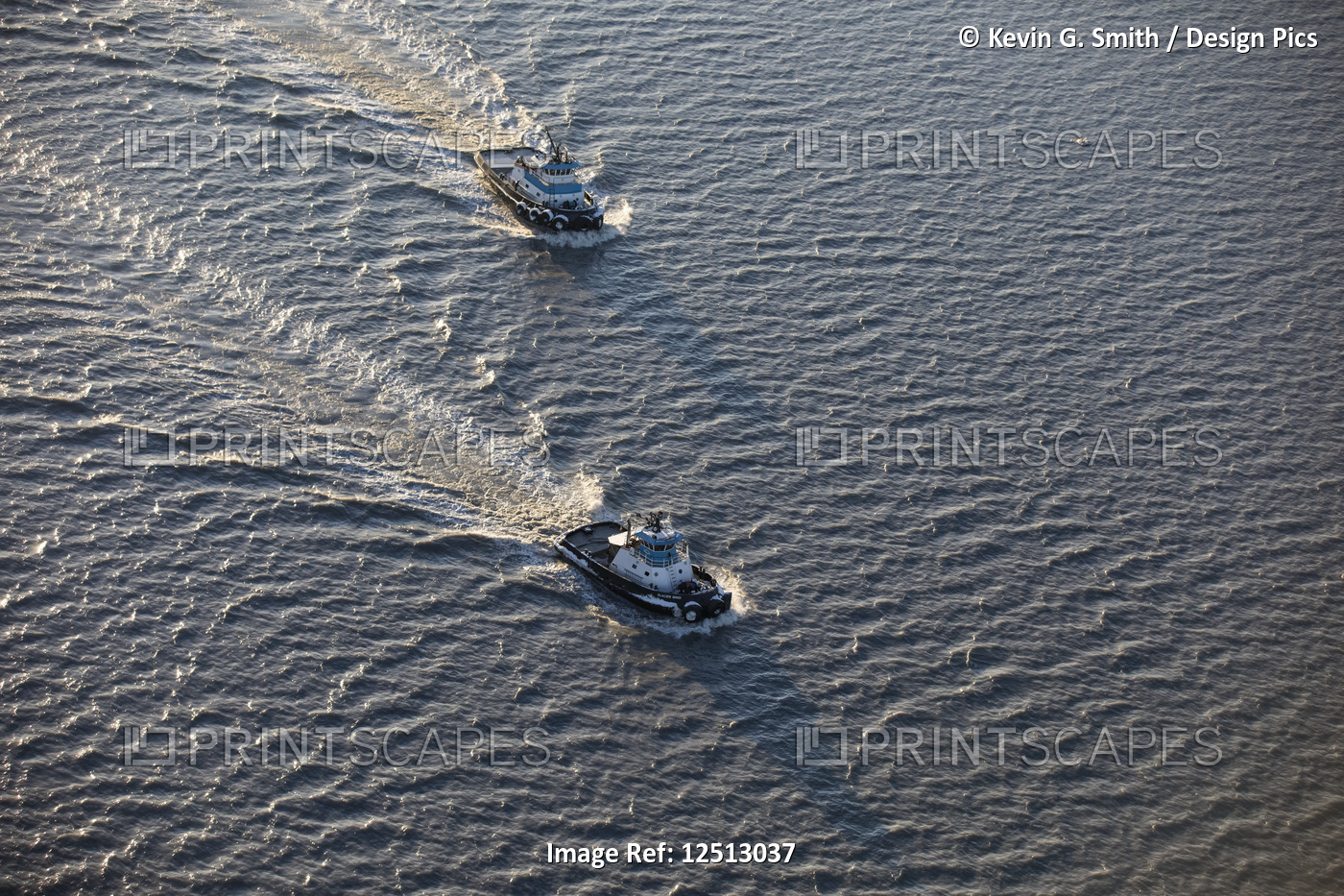 Aerial view of two tug boats sailing on the silty waters of Cook Inlet in late ...