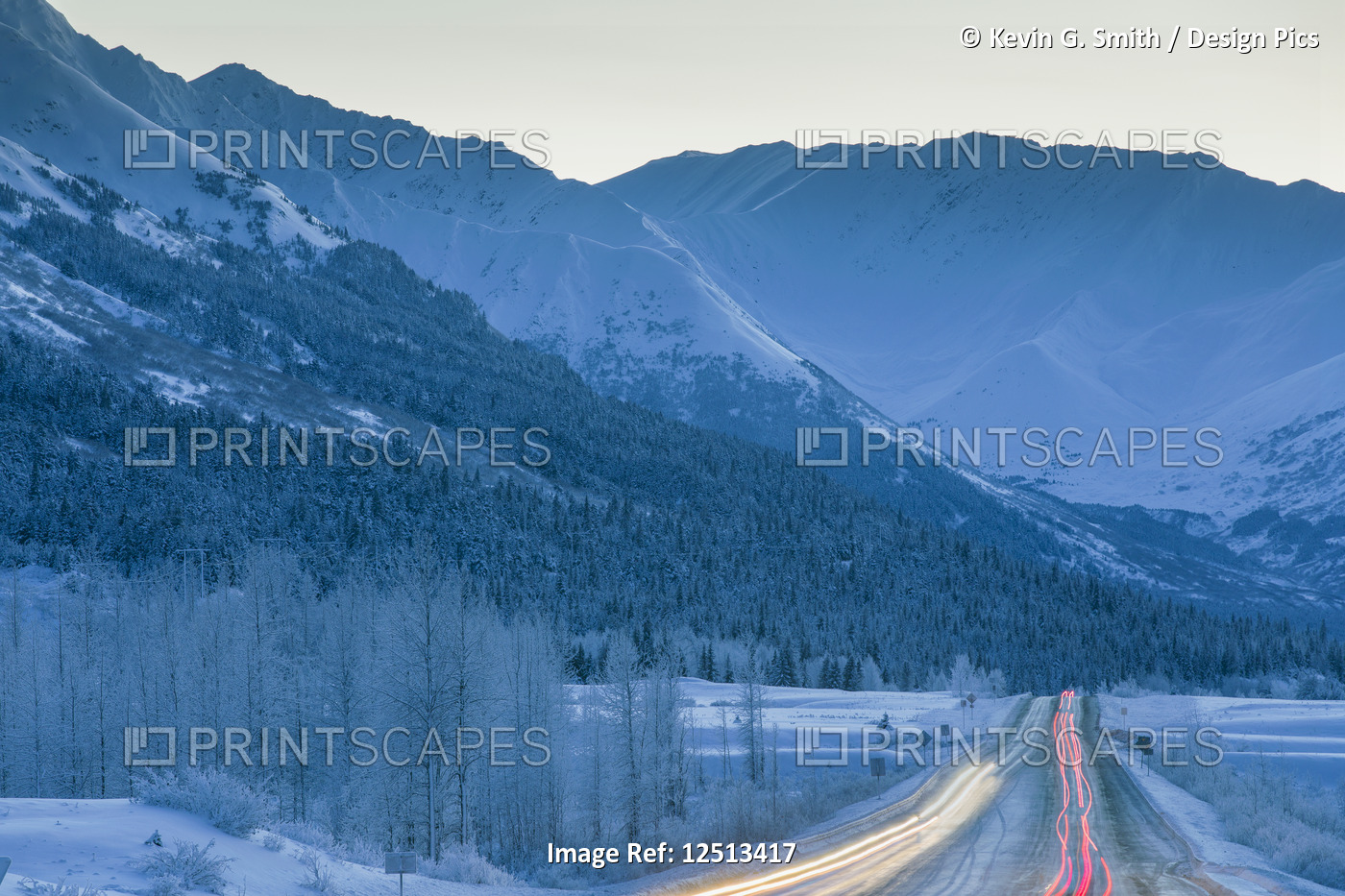 Car lights are blurred down the Seward Highway at dusk in winter, Turnagain ...