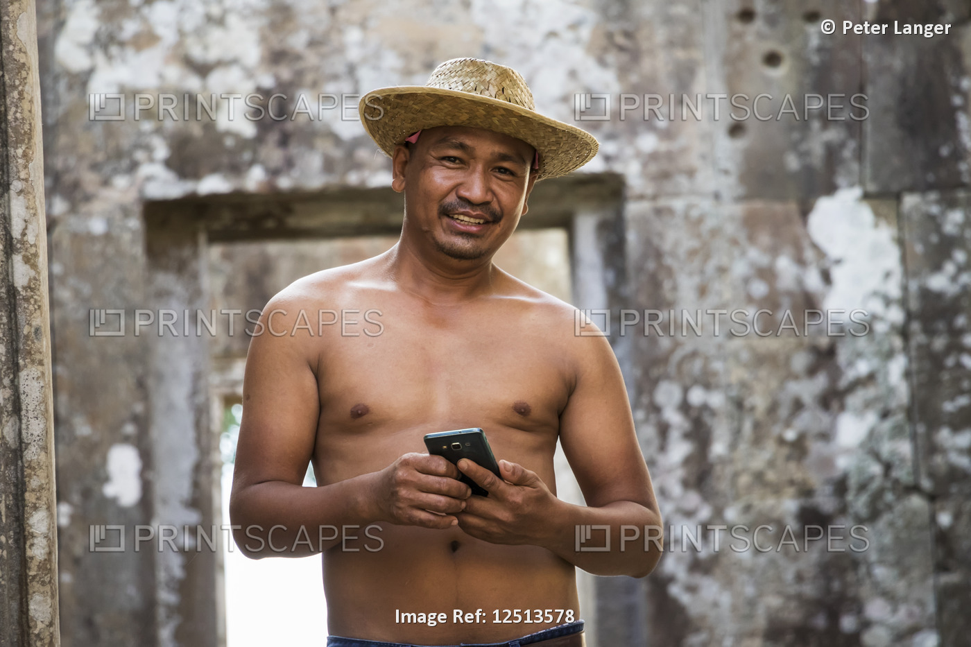 A shirtless Cambodian man holding a smart phone at Preah Vihear; Preah Vihear, ...