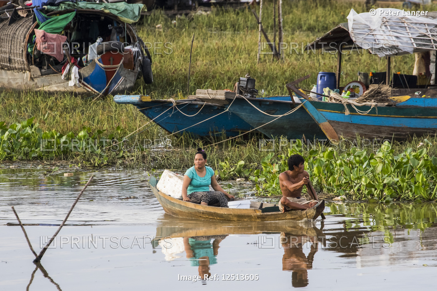 Man and woman in a boat by a floating village in the Tonle Sap; Siem Reap, ...