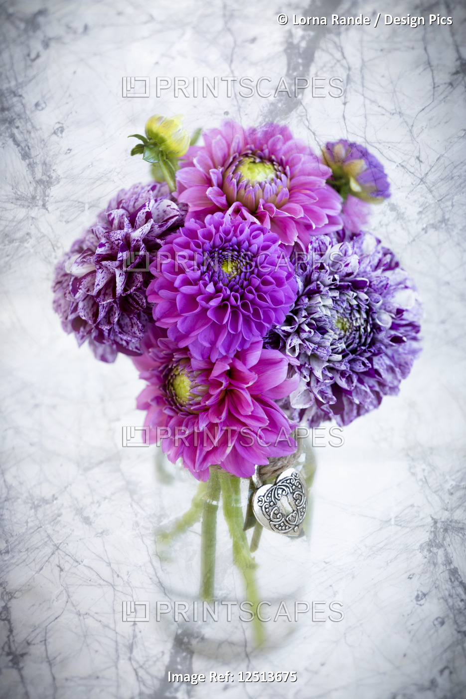 Purple marbled dahlia's arranged in a glass jar on a marble counter
