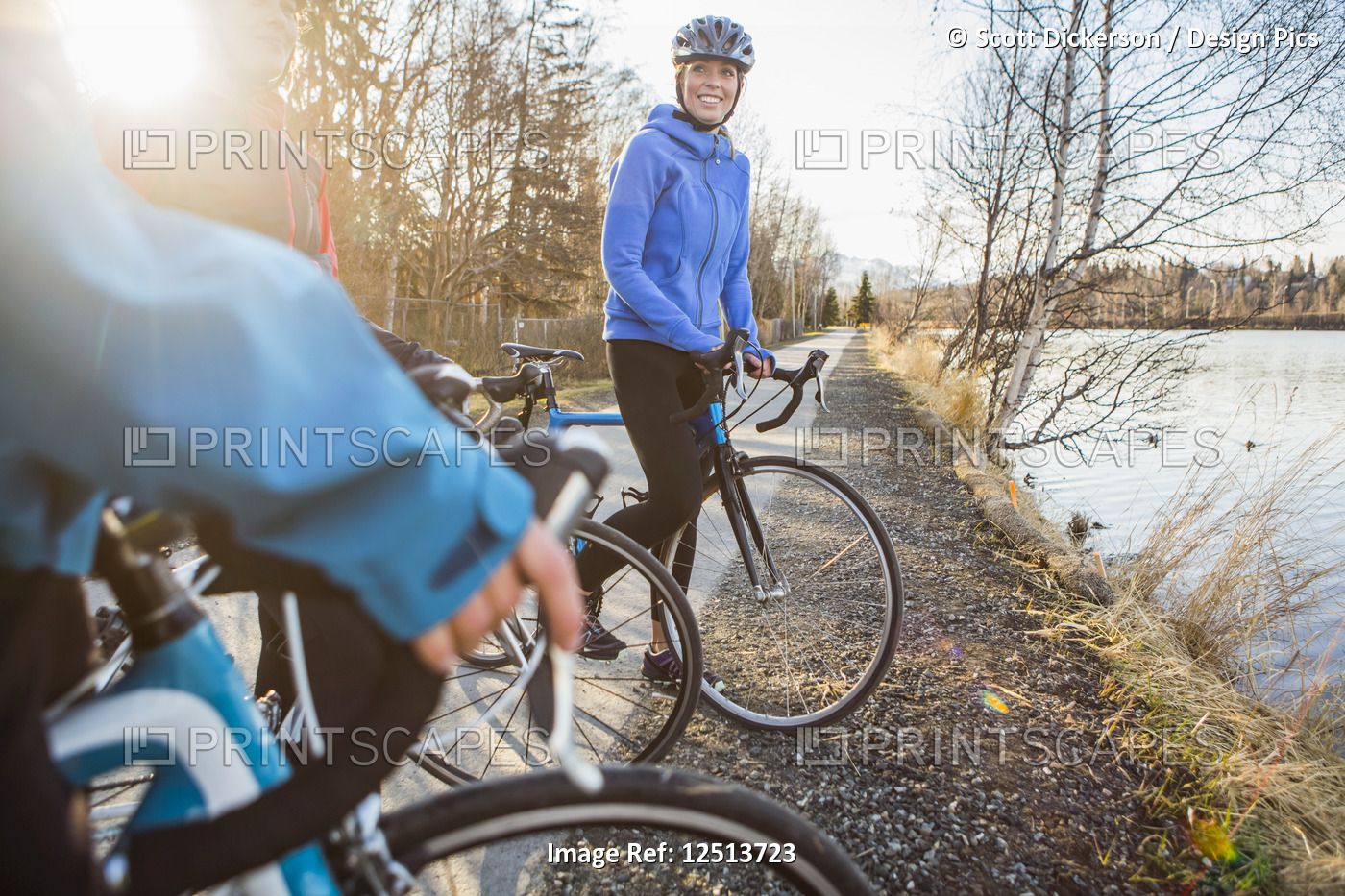 Three young women on their bicycles on a trail at sunrise; Anchorage, Alaska, ...