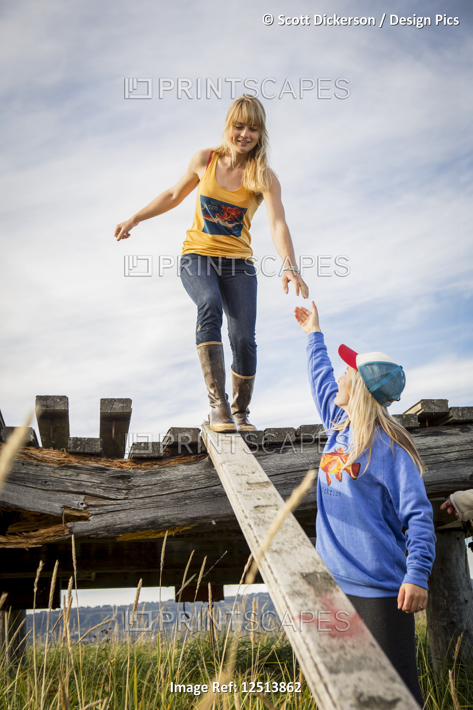 Two sisters explore an old wooden pier near Homer, South-central Alaska; Homer, ...