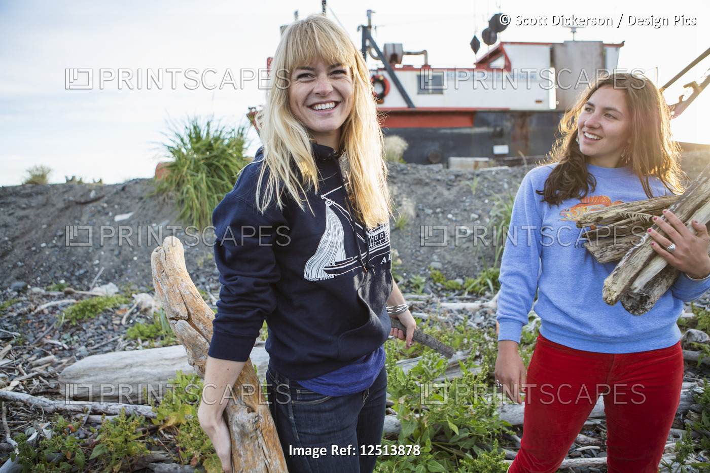 Two young women gathering firewood along coastal Homer, South-central Alaska; ...