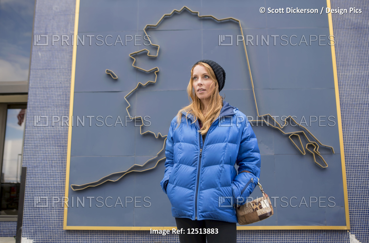 Mid adult woman standing in front of a 3D graphic of the outline of Alaska on a ...