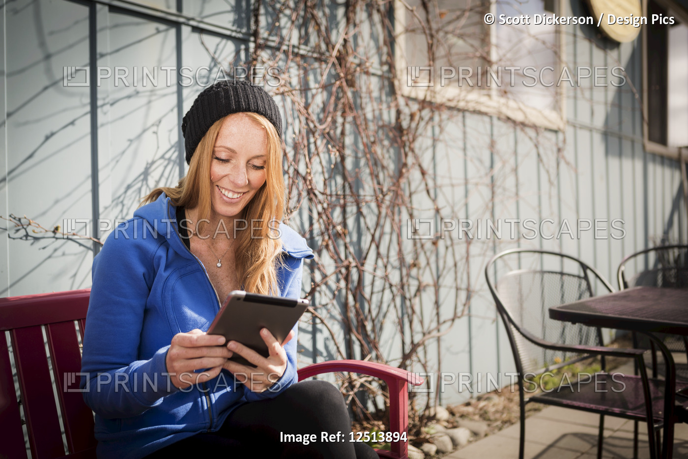 Young woman sitting with her tablet outside a business in downtown Anchorage, ...