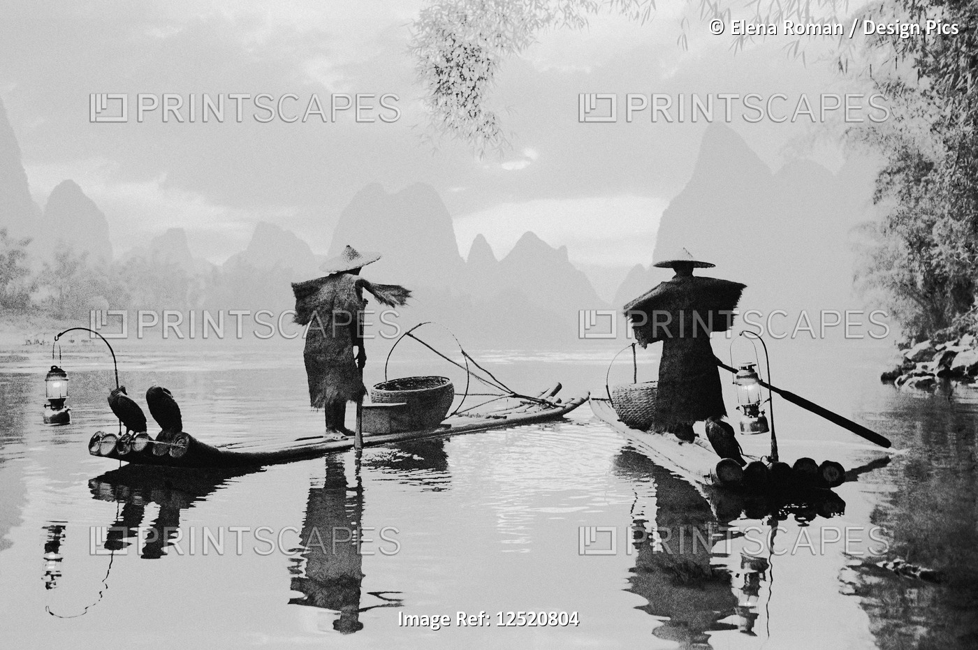 Black and white image of fishermen standing on boats on a tranquil river in the ...
